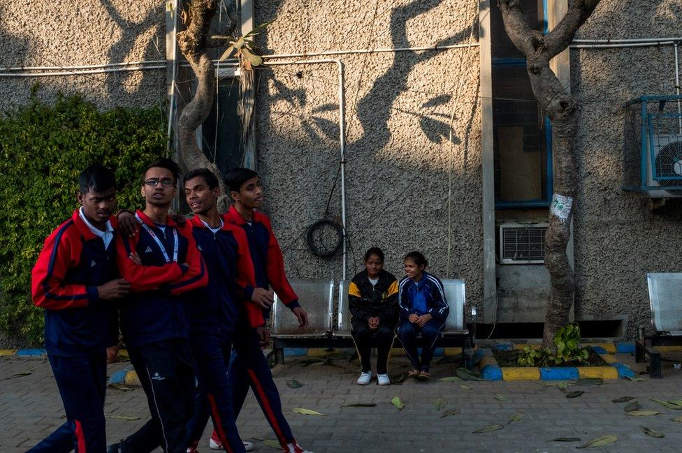 A group of boys pass by two girls.