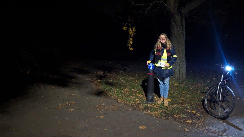 Jennifer Huygens with her bicycle in a a dark Fairlands Valley Park, Stevenage