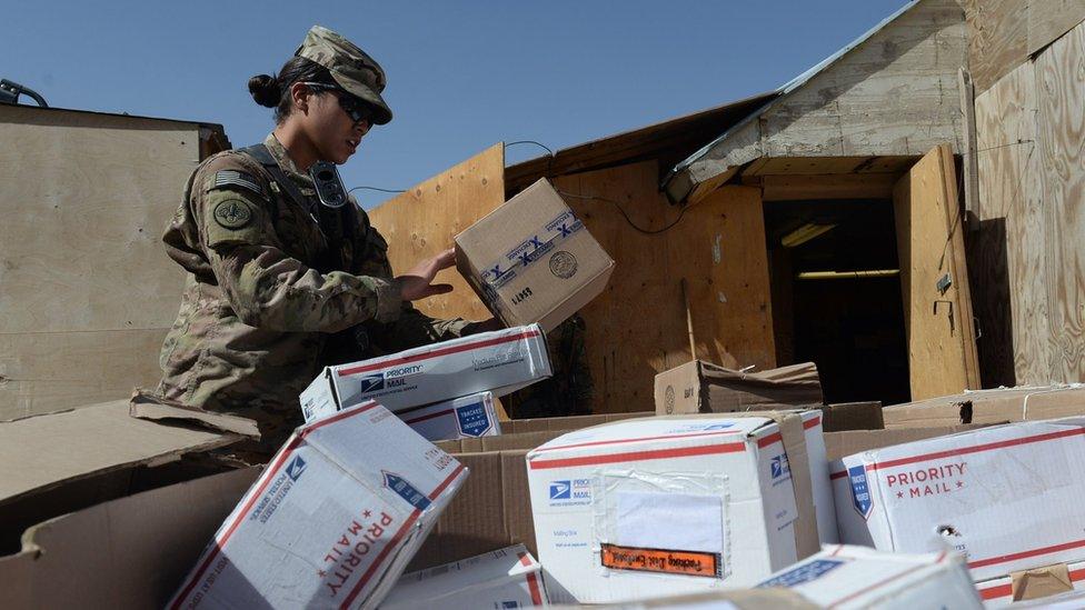 A US soldier sorts packages at a US base in Afghanistan, August 2014