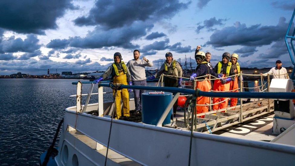 The crew of the Scottish scallop trawler "Cornelis-Gert Jan" stand on the deck as they leave the northern French port of Le Havre