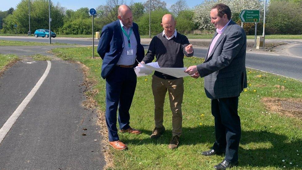 Three men stood at side of ring road