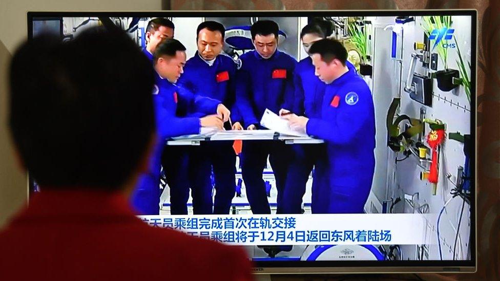 Citizens watch TV news showing the Chinese astronaut crew completing the first in-orbit handover in Fuyang City, Anhui Province, China, December 3, 2022.