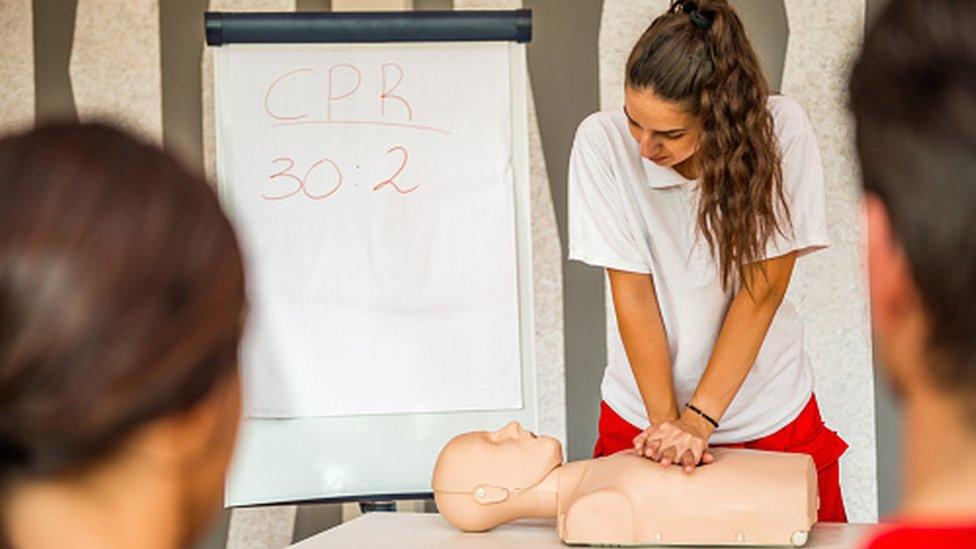 teacher teaching CPR to students in classroom