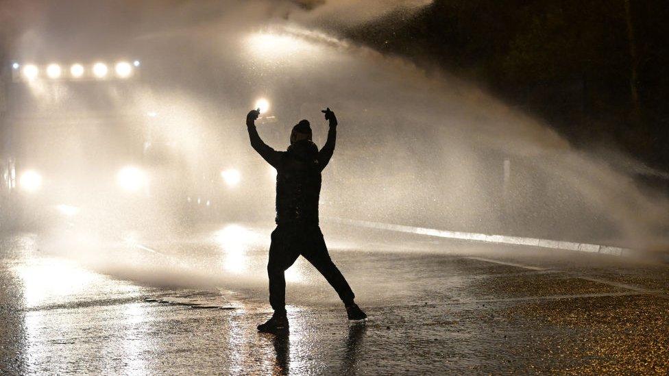 Silhouette of young person in front of water canon