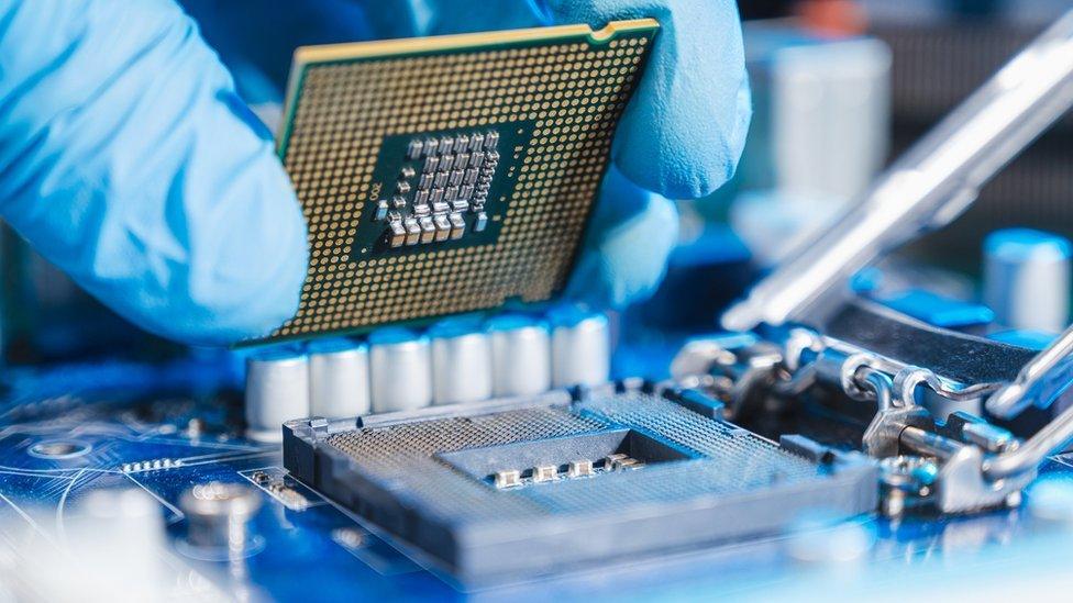 A technician laying a CPU chip in the motherboard socket.