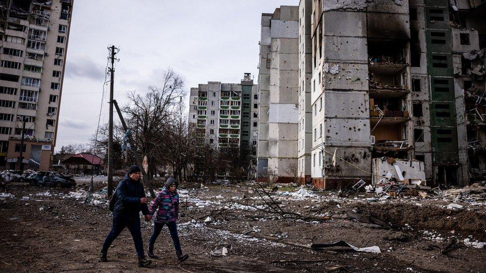 Residents walk in front of residential buildings damaged in shelling in Chernihiv on 4 March