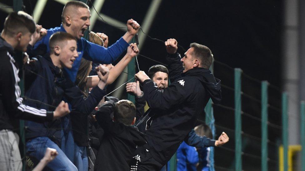 Crues manager Stephen Baxter joins supporters in celebration as the club retains the league title for the first time