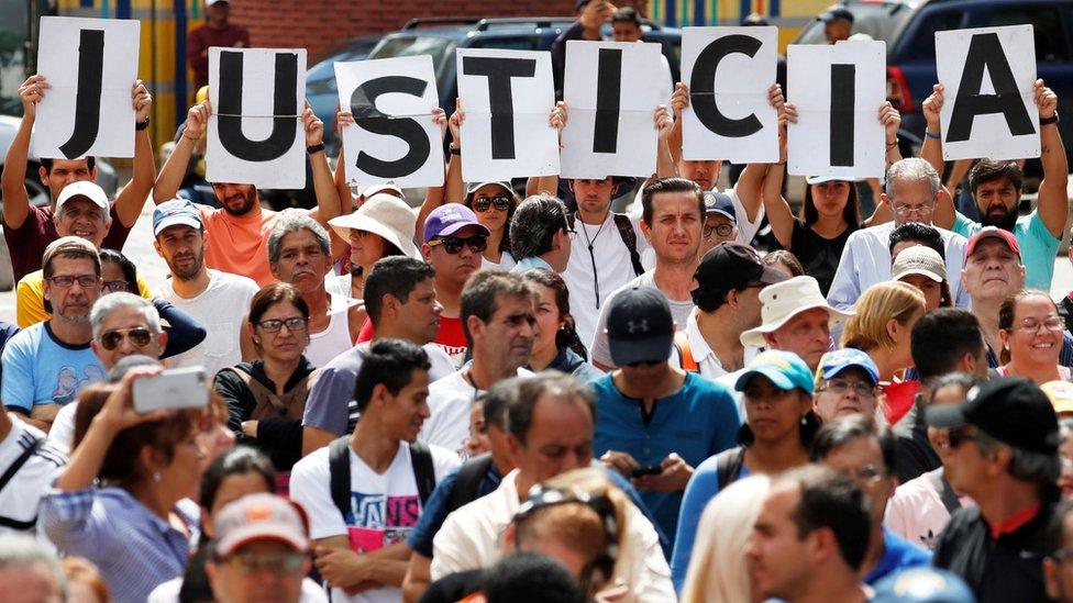 Supporters of Venezuela's opposition leader Juan Guaido hold letters which read "Justice" during a rally