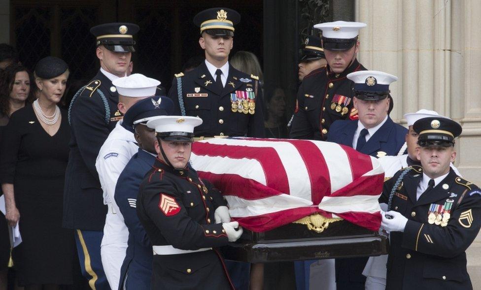 The McCain family and an honour guard in military uniforms pictured with his flag-draped casket