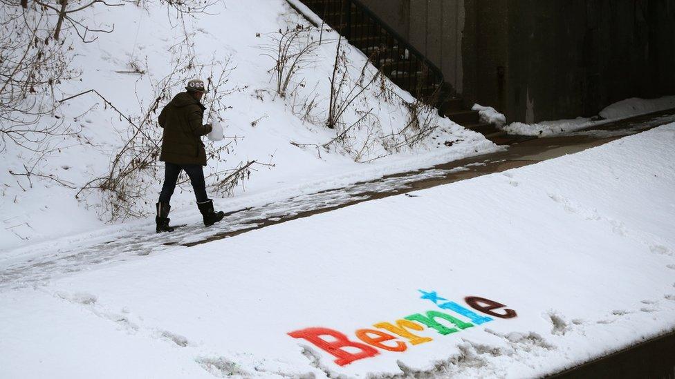 A man walks past a sign in the snow for Democratic 2020 U.S. presidential candidate and U.S. Senator Bernie Sanders in Ames, Iowa, U.S., January 25, 2020