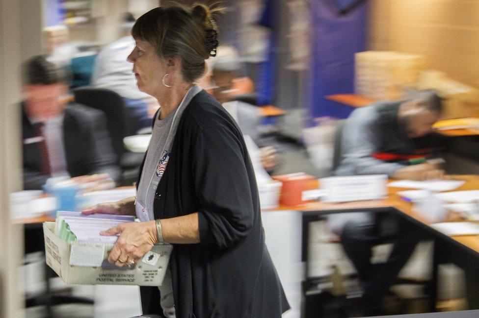 Johanna Stiles carries vote-by-mail ballots after the Leon County, Florida