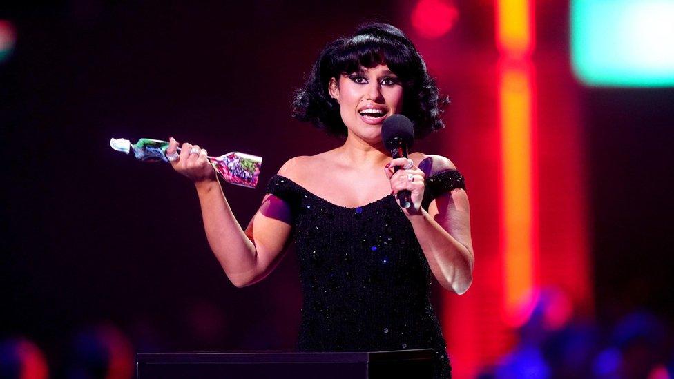 Raye smiling and holding a Brit award