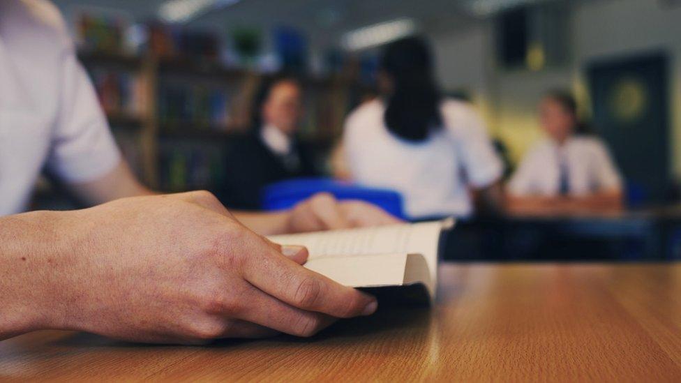 Pupil holds a book in a school library