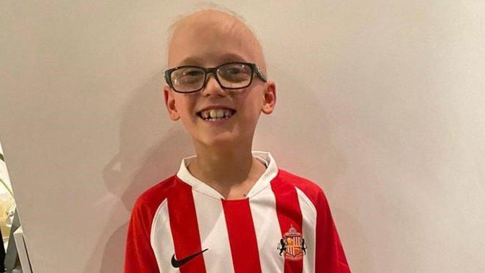 A boy smiles while wearing a Sunderland shirt