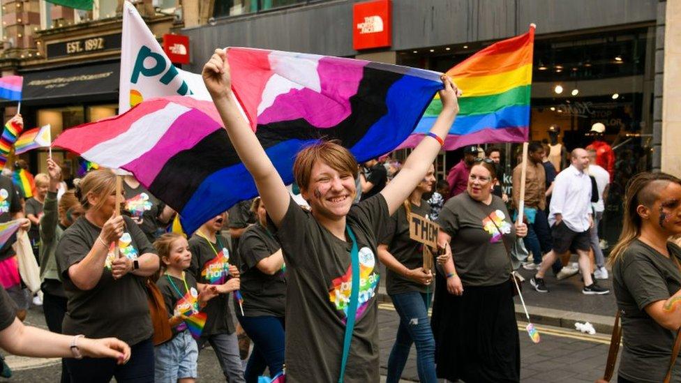 Paraders smile at the camera as they wave bannes