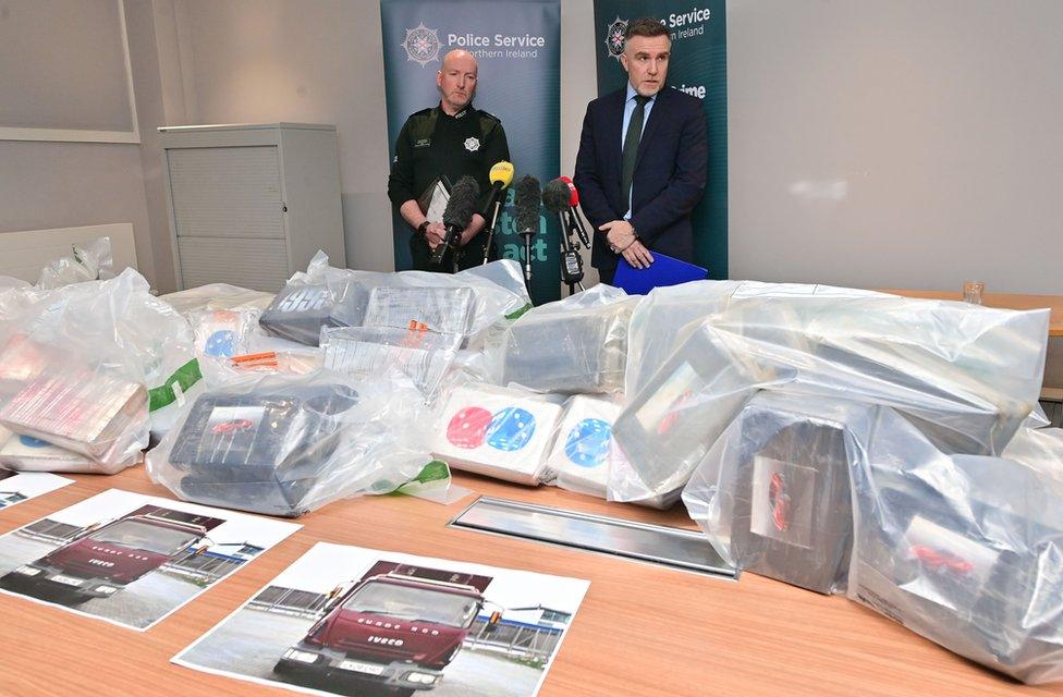 Police officers speak to the media with bags of the cocaine on a table