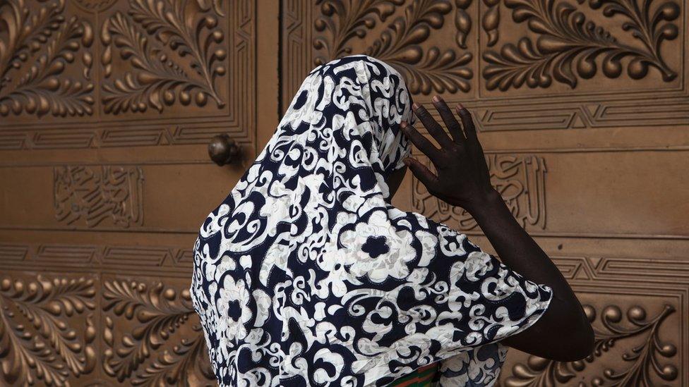 Woman stands outside mosque entrance