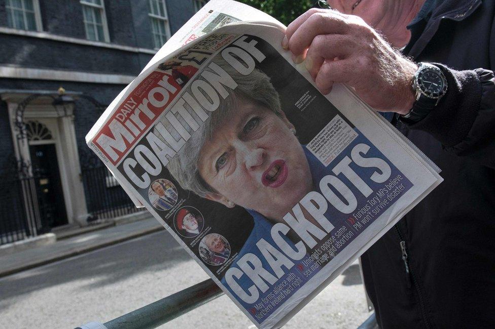 A cameraman holds Saturday's Daily Mirror front page outside No 10 Downing Street