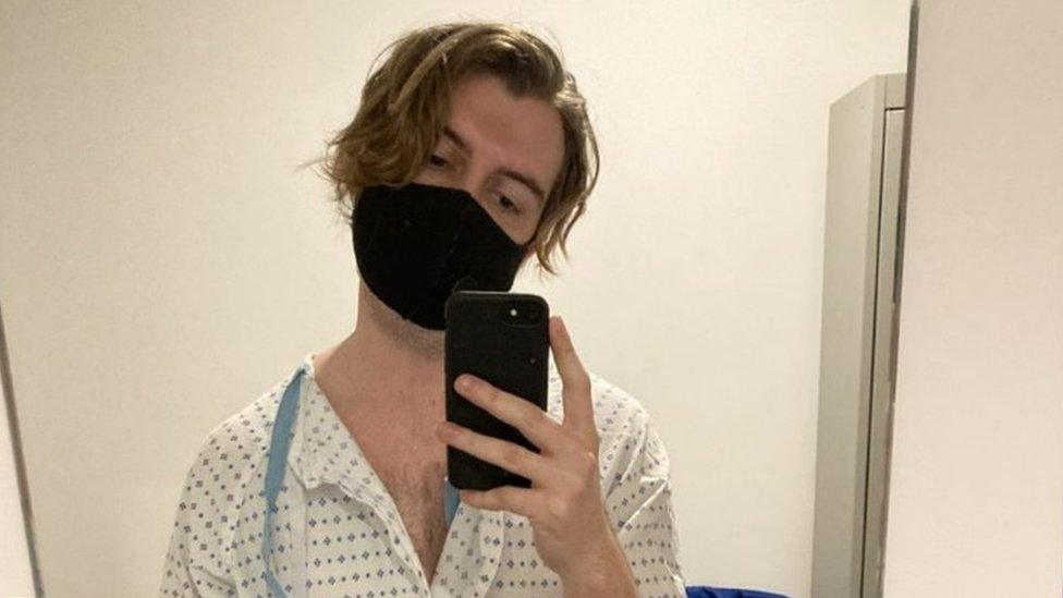 Photo of Charlie Russell in a hospital gown and mask while waiting for tests in 2020.