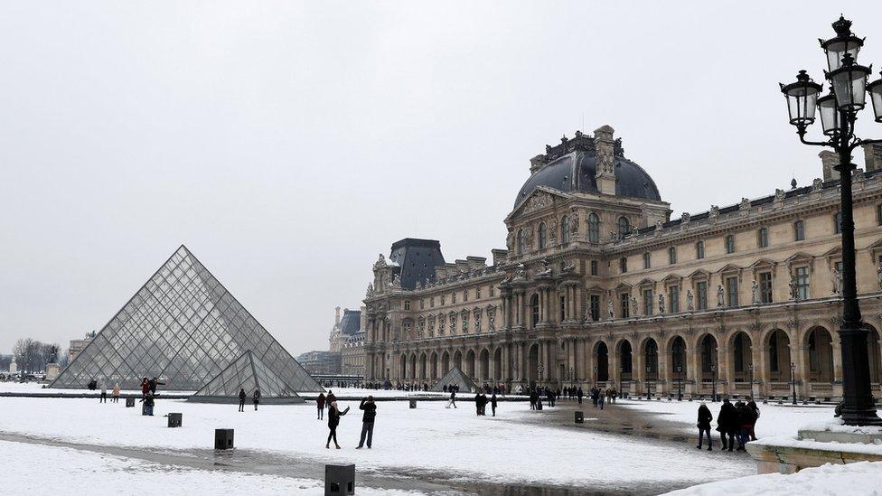 Tourists walk in the snow at the Louvre Pyramid in Paris February 9, 2018.