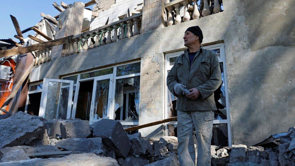 A man removes debris from a building destroyed by shelling in Luhansk, eastern Ukraine