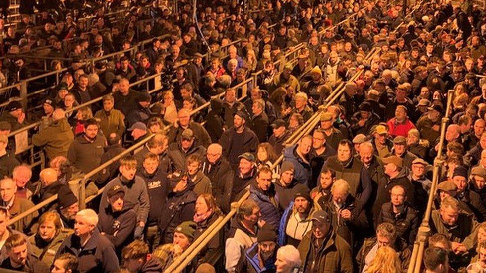 Thousands of people in a livestock mart