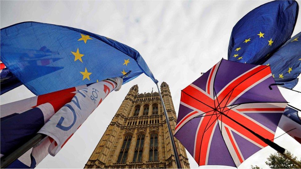 EU flags and Union flag-themed umbrellas fly outside the Houses of Parliament in London on 23 October 23, 2019.