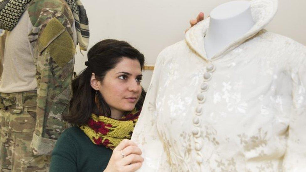 A museum worker puts a wedding dress on display