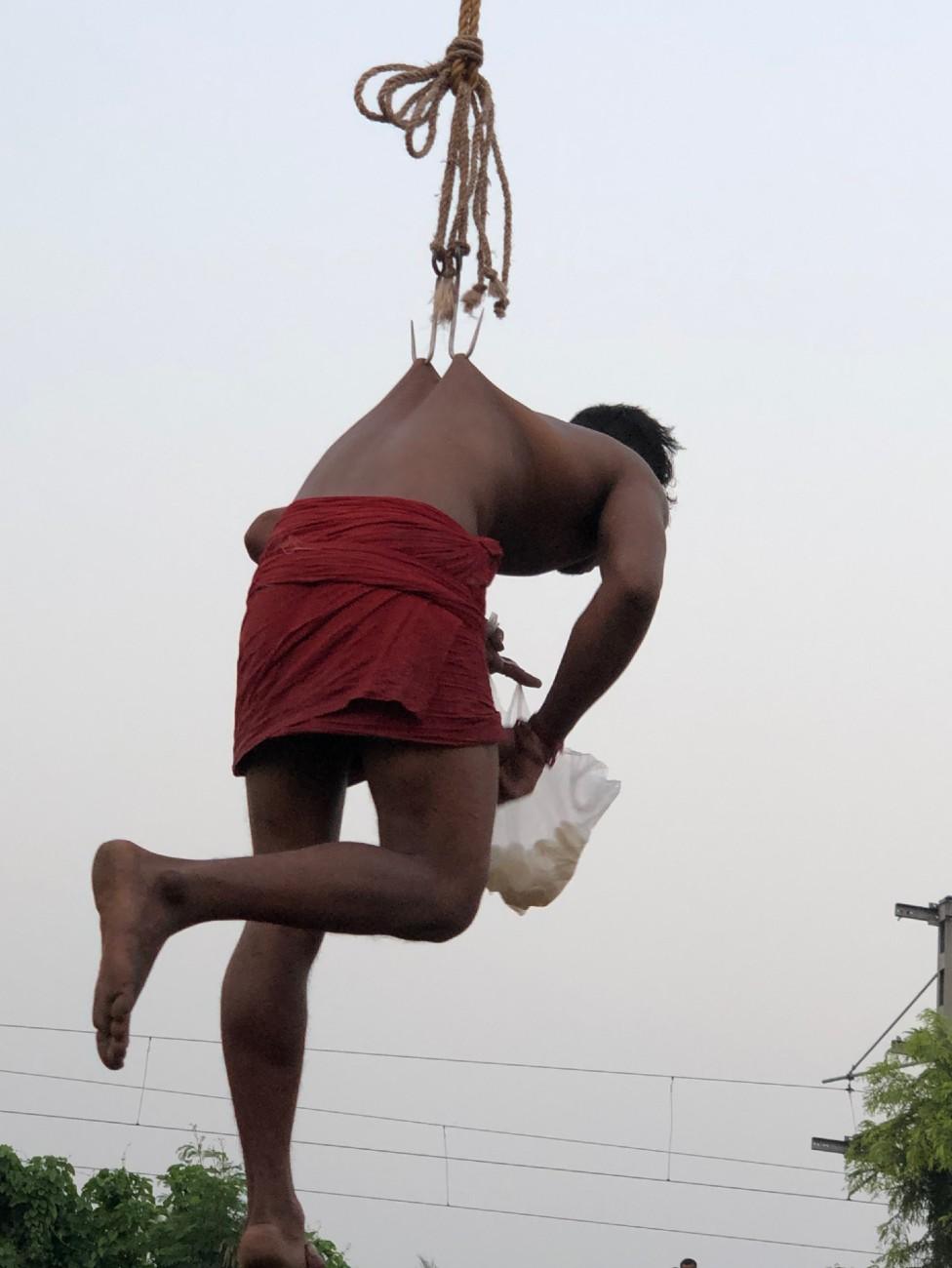 A charak devotee holding a bag of sweets that he will scatter in the crowd