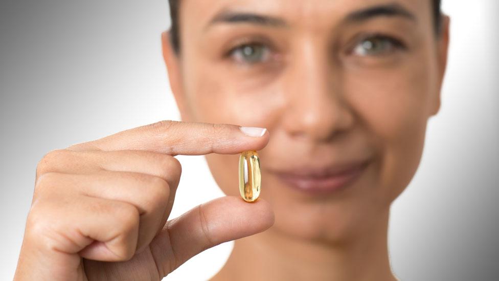 Stock image of a woman holding a supplement