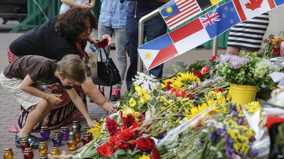 A woman and a young boy place flowers in commemoration of the victims of Malaysia Airlines MH17 plane accident in eastern Ukraine