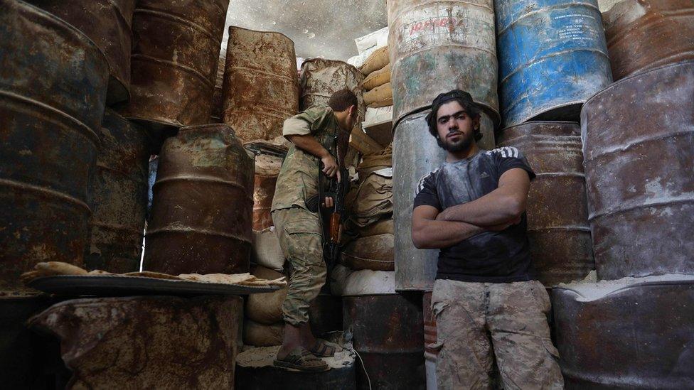 Syrian rebel fighters stand next to an improvised barricade in the western outskirts of Aleppo (10 September 2018)