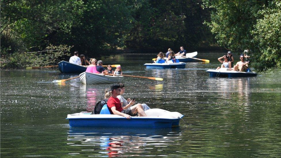 People enjoy hot weather on the boating lake in Victoria Park, London