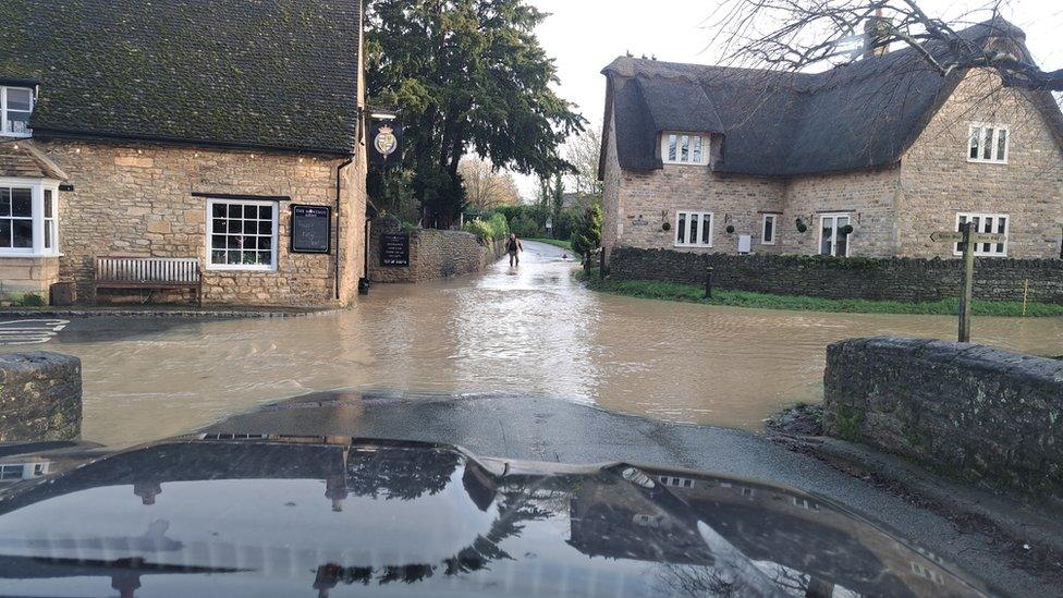 A rural road junction with water flowing along the roads past stone houses