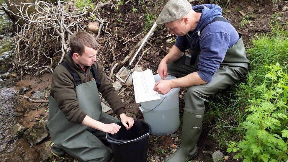 Two men carrying out checks on the riverbank