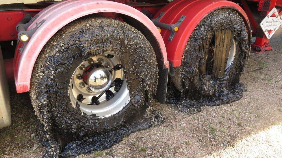 Two wheels of a truck coated in tar