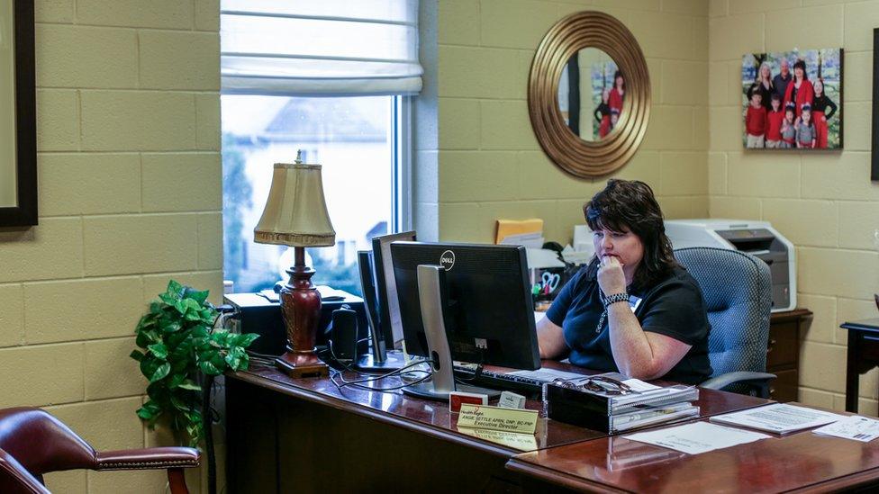 Angie Settle sits at her desk