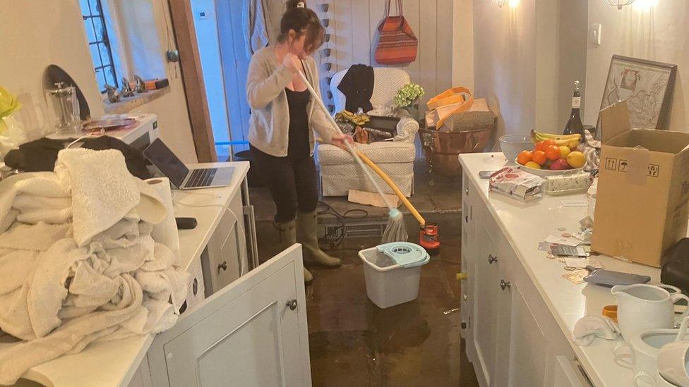 A woman mopping flood water in her Wiltshire home