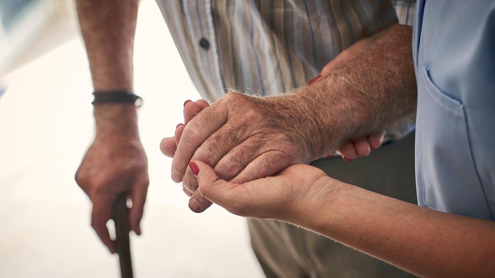 Elderly man being helped by carer