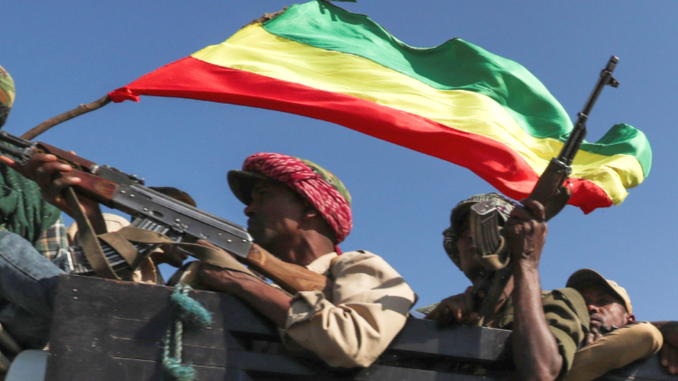 Armed fighters in a truck holding an Ethiopian flag