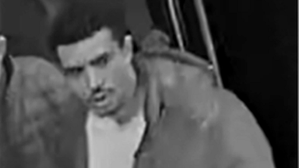 CCTV image of a man with a moustache wearing a light-coloured jacket