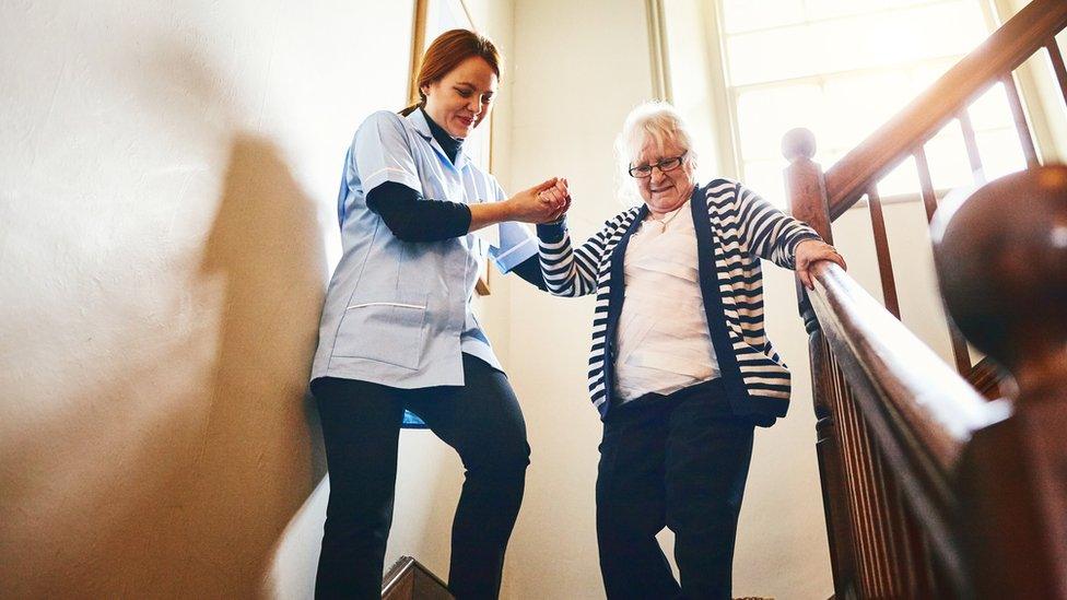 Caregiver helping an older woman walking down stairs