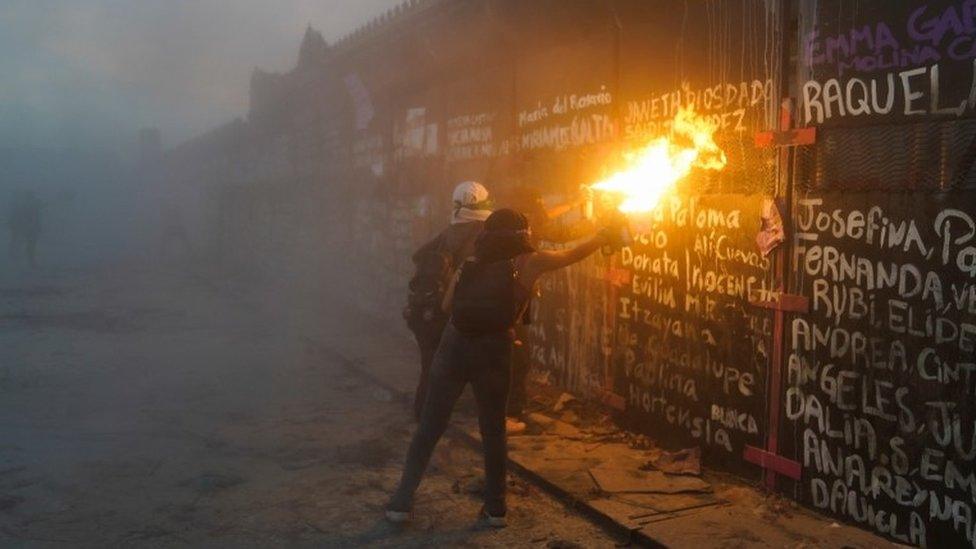 Women try to take down the fences placed outside the National Palace