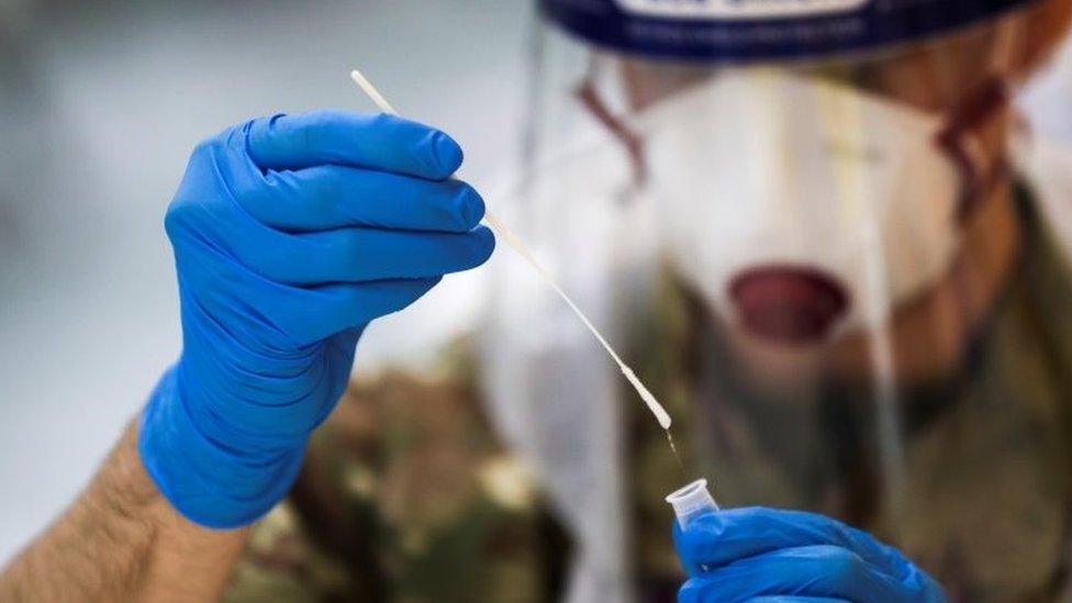 A member of the British Royal Air Force holds a lateral flow antigen test swab sample