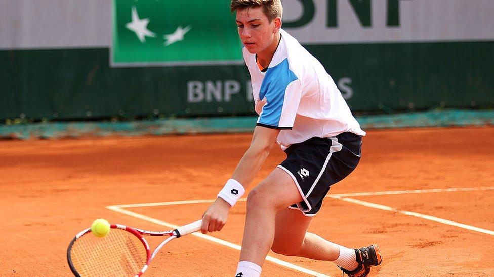 cameron norrie reaches to hit a ball with his racket playing on a clay court