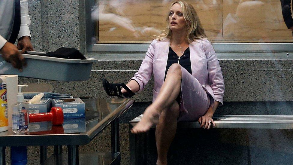 Adult-film actress Stephanie Clifford, also known as Stormy Daniels, puts her shoe back on after passing though a security screening