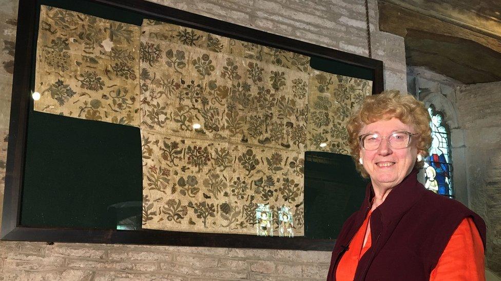 Ruth E. Richardson with the copy of the cloth now hanging on the church wall