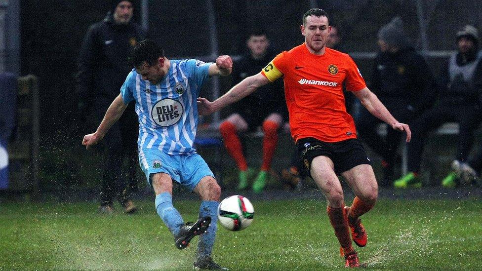 Warrenpoint Town's Conor McDoanld clears as Carrick's Aaron Harmon closes in