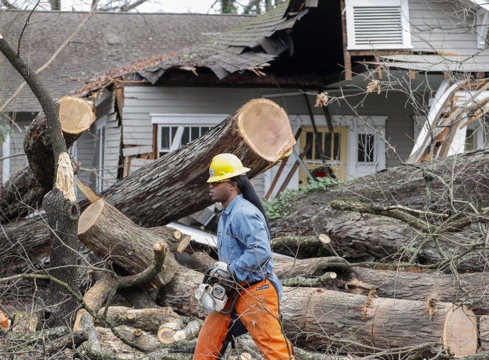 Terrance Miller with East Point Power helps clear a large tree which fell and hit a home and several cars as thunderstorms moved through East Point, Georgia, on 3 January 2017.