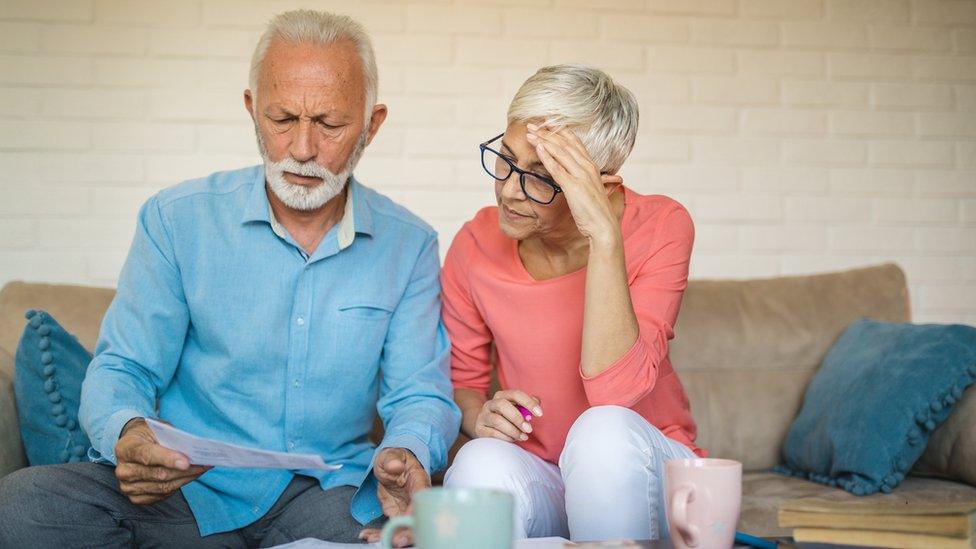 A couple look through financial paperwork on the sofa